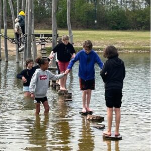 De minoren bewandelen een waterparcours tijdens de trainingkamp